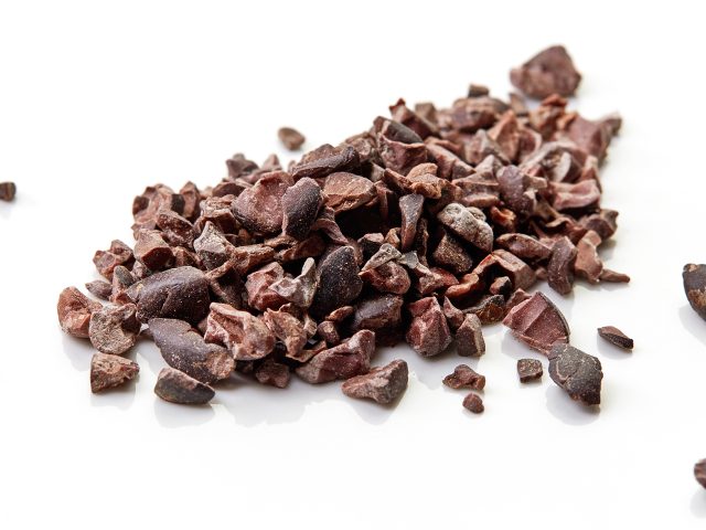 Heap of cacao nibs, isolated on white background